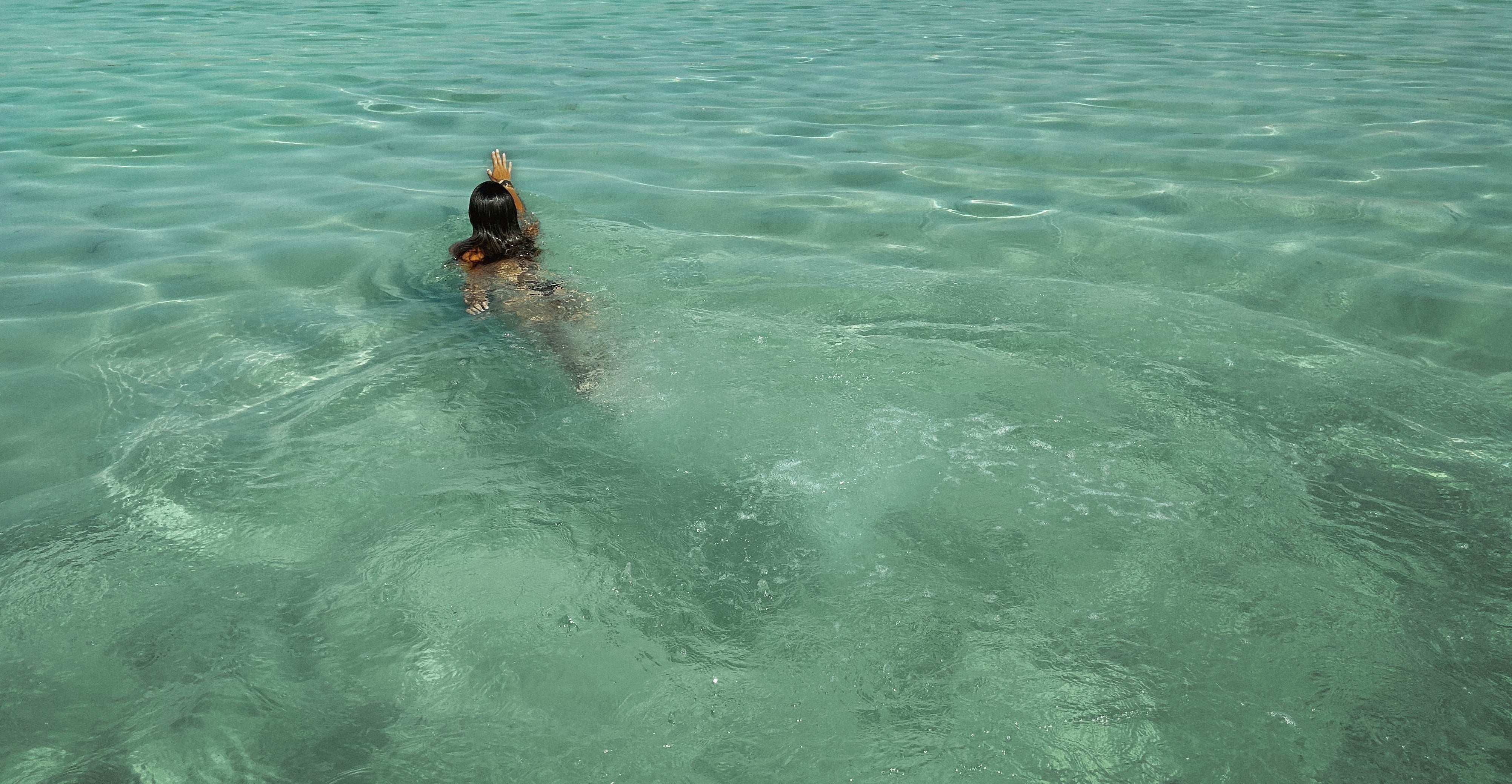 Women swiming in blue waters of Bulgari Island and going to wear Mermaids Club beach robes.